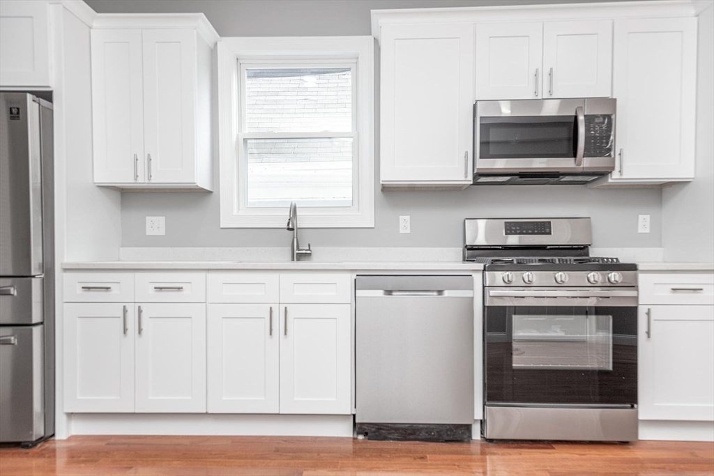 16 Gaston Street, Unit 2F Boston, MA 02121 - Photo 2 of 7 a kitchen with stainless steel appliances granite countertop a stove a microwave and a white cabinets