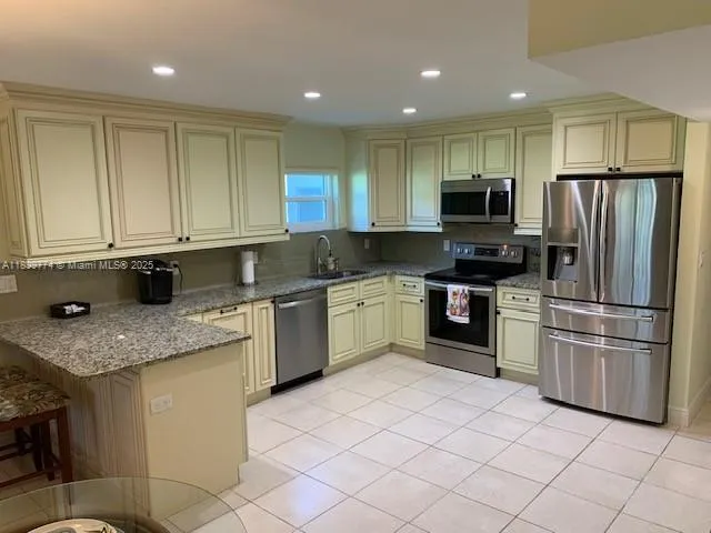 a kitchen with a sink a microwave a refrigerator and cabinets