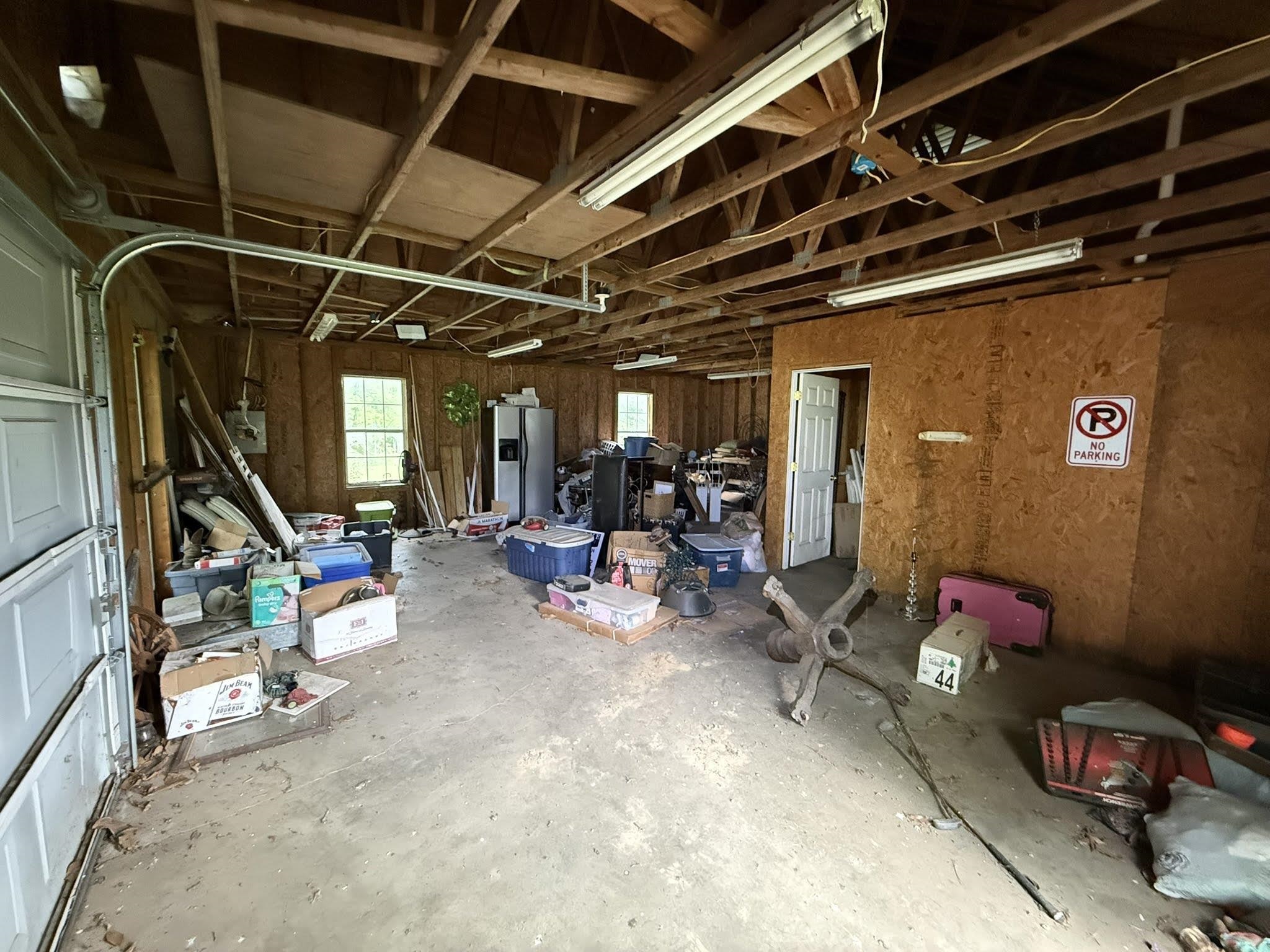 2102 Campbell Road Millington, TN 38053 - Photo 9 of 18 Spacious garage structure featuring exposed wood beam ceiling, concrete flooring, multiple windows, fluorescent lighting, and a white interior door