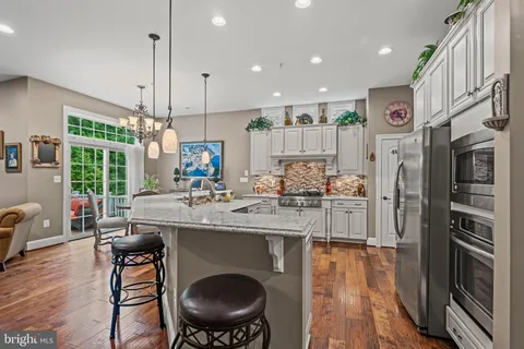 a kitchen with stainless steel appliances kitchen island granite countertop a sink and refrigerator
