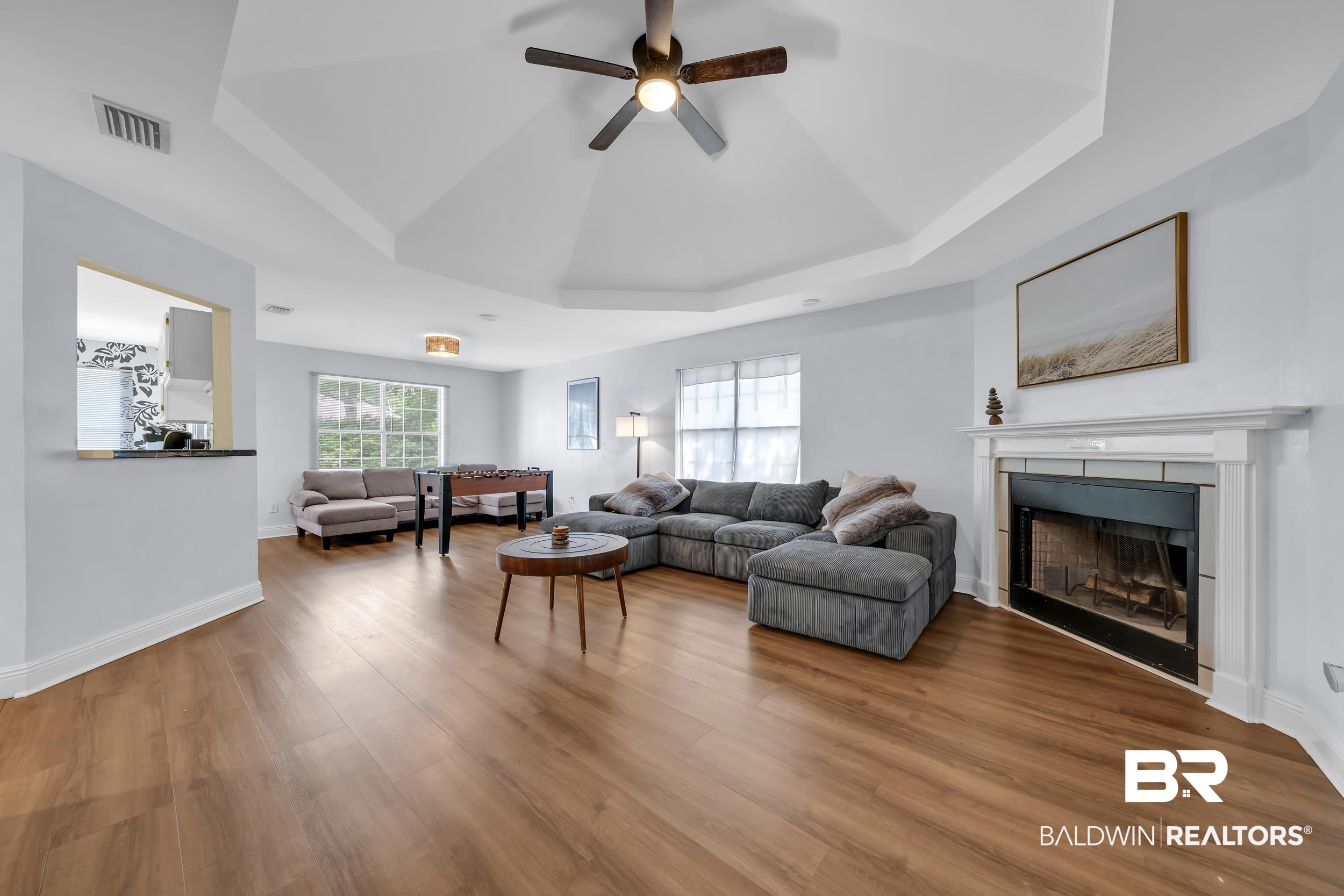 509 Loblolly Court Foley, AL 36535 - Photo 3 of 26 Spacious living area featuring wood-finish flooring, a tray ceiling with a ceiling fan, and a fireplace with a white mantel