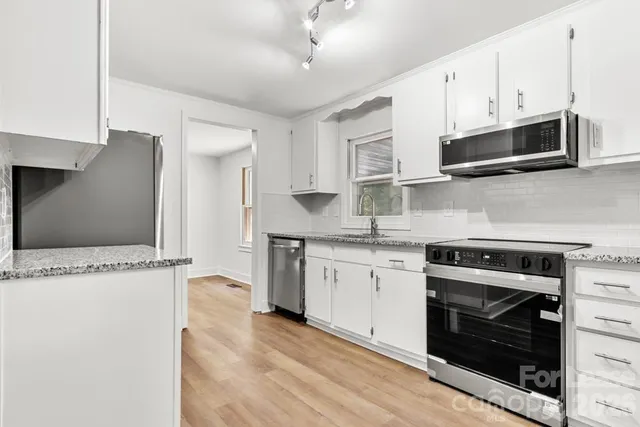 a kitchen with stainless steel appliances granite countertop a stove a microwave and a refrigerator