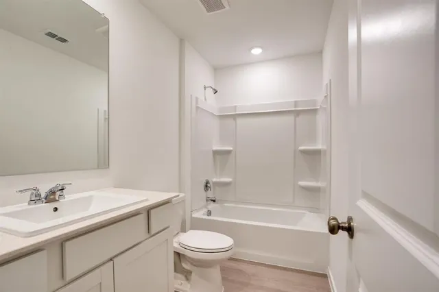 a bathroom with a bathtub shower sink vanity mirror and toilet