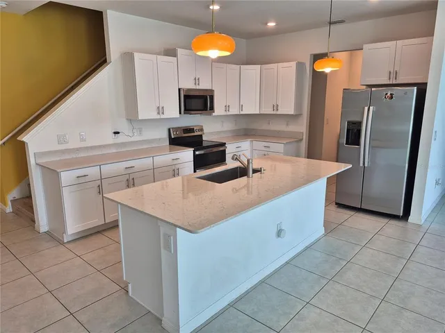 a kitchen with stainless steel appliances granite countertop a sink a microwave a refrigerator and white cabinets