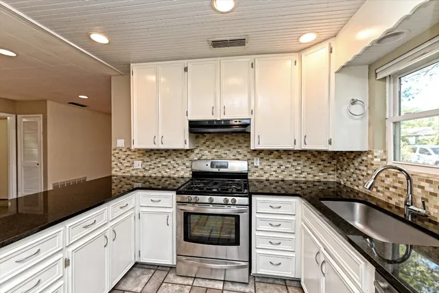 a kitchen with granite countertop a stove sink and cabinets