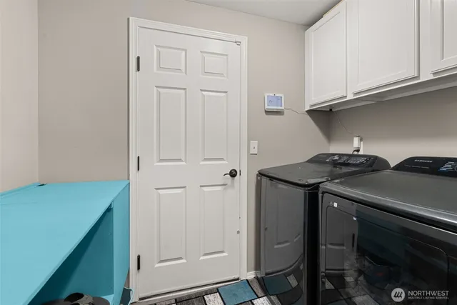 a utility room with granite countertop cabinets washer and dryer