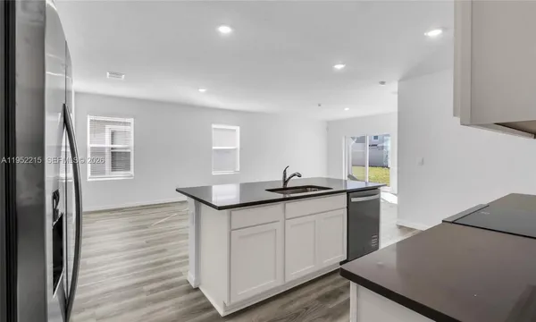 a kitchen with stainless steel appliances granite countertop a refrigerator a sink dishwasher a stove and a microwave oven on the granite countertops