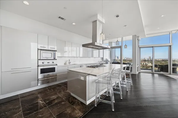 a kitchen with stainless steel appliances kitchen island granite countertop a stove a sink a refrigerator and white cabinets with wooden floor