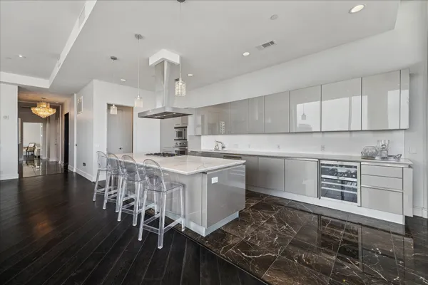 a kitchen with a stove a sink and white cabinets with wooden floor