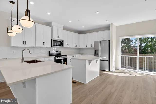 a kitchen with kitchen island granite countertop a stove a sink a refrigerator and white cabinets with wooden floor