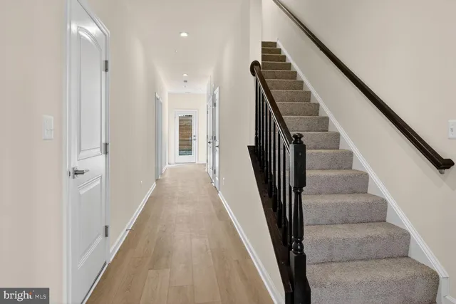 a view of a hallway with wooden floor and stairs