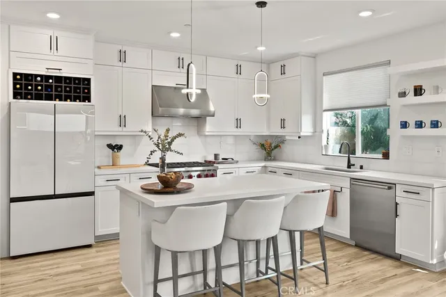 a kitchen with stainless steel appliances granite countertop a sink a stove a refrigerator and island with wooden floor