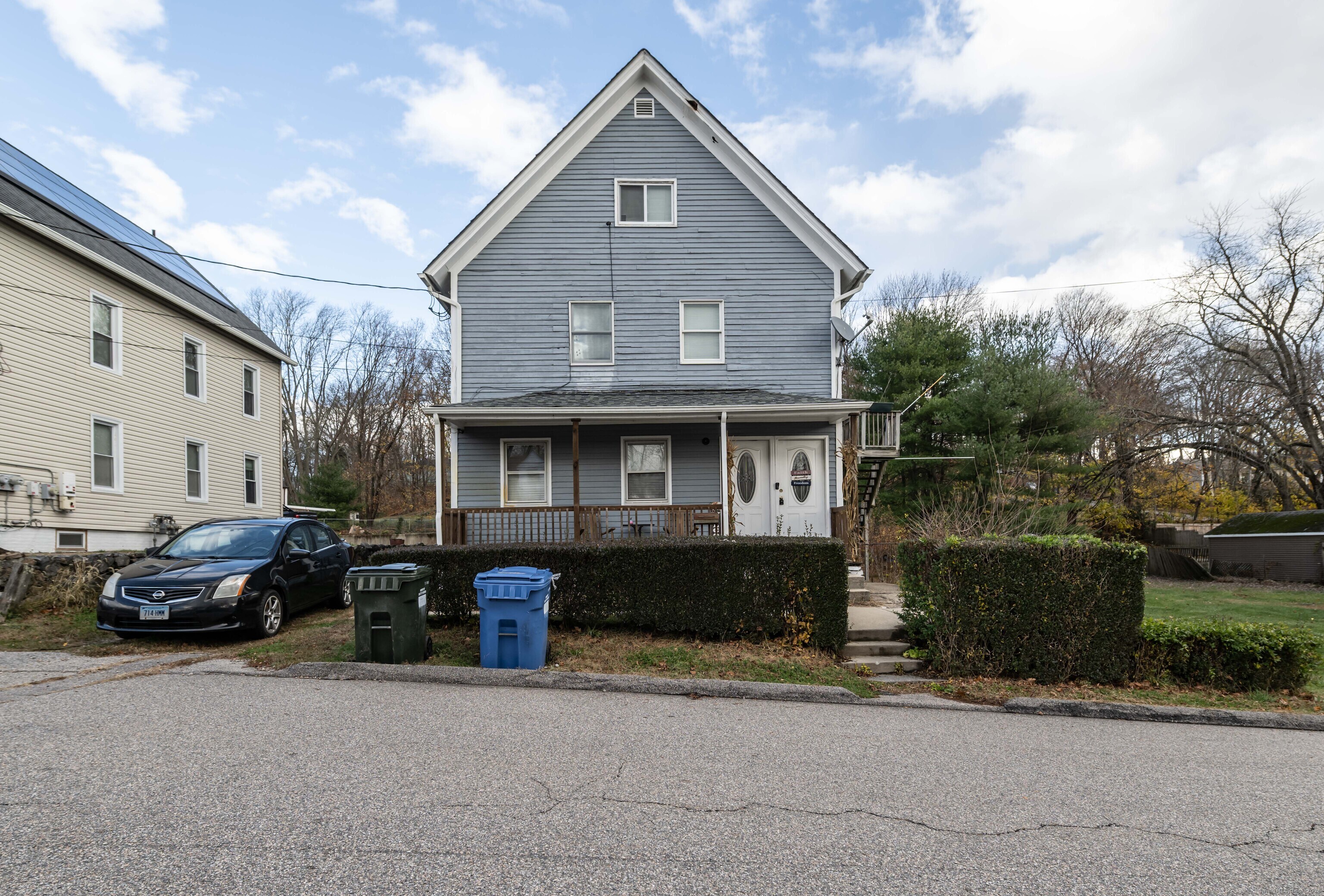 a front view of a house with cars parked on road