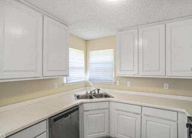 a kitchen with granite countertop white cabinets and sink