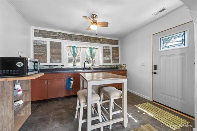 a kitchen with granite countertop wooden cabinets a dining table and appliances
