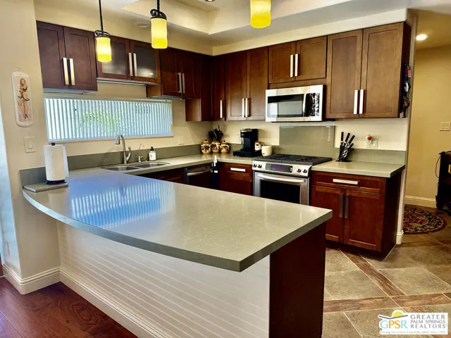 a kitchen with kitchen island granite countertop a sink dishwasher stove and oven with wooden cabinets