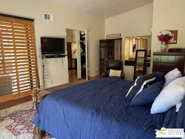 a bedroom with a bed a flat screen tv and dresser