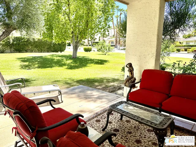 a view of a patio with lawn chairs under an umbrella next to an ocean