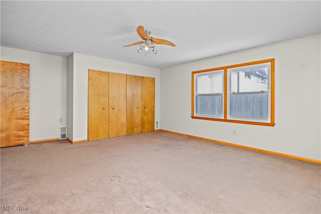 14015 West Lake Road Vermilion, OH 44089 - Photo 28 of 50 Unfurnished bedroom featuring carpet flooring, a closet, a ceiling fan, and a textured ceiling