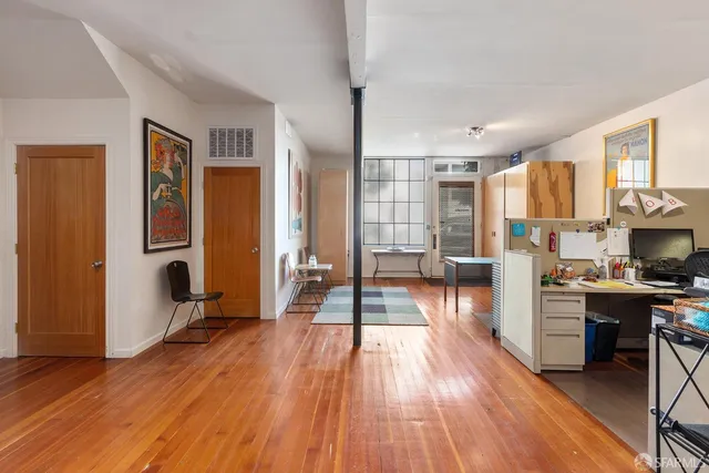 a view of a kitchen with kitchen island wooden floors stainless steel appliances and windows