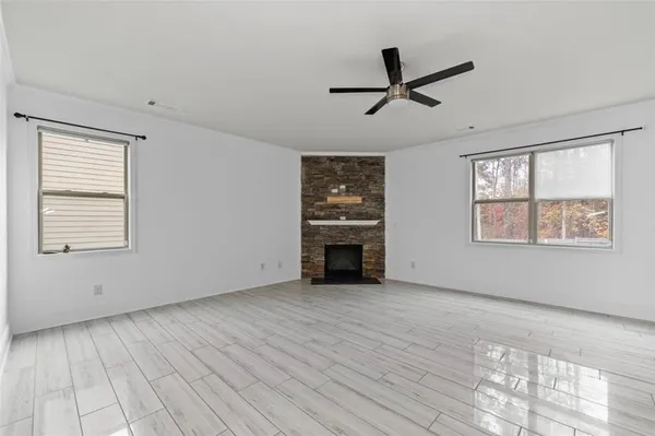 a view of an empty room with a window and wooden floor