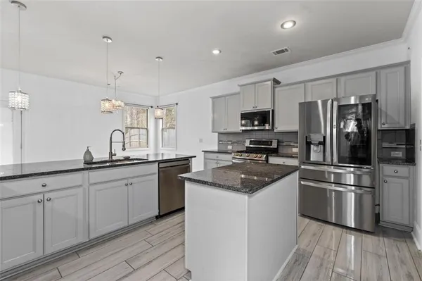 a kitchen with granite countertop a sink stainless steel appliances and cabinets
