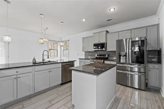 a kitchen with granite countertop a sink stainless steel appliances and cabinets