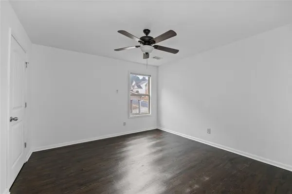 an empty room with wooden floor fan and windows