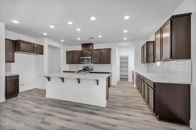 a kitchen with stainless steel appliances kitchen island granite countertop a stove a sink and a refrigerator