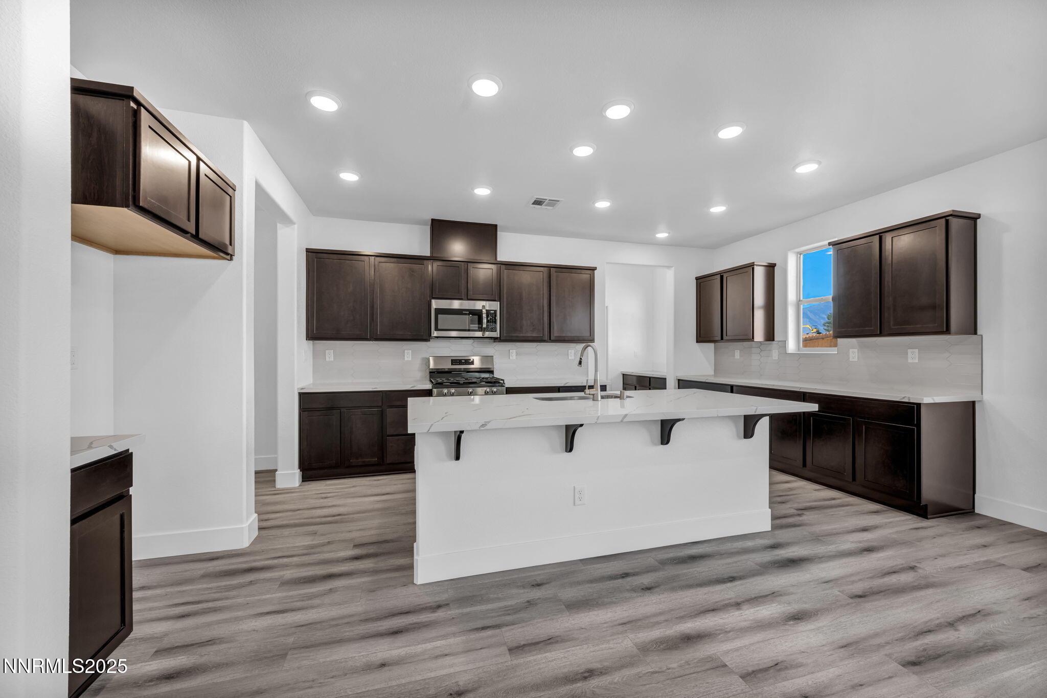 1322 Nebula Road, Unit HOMESITE 92 Carson City, NV 89705 - Photo 3 of 22 a large kitchen with stainless steel appliances kitchen island a sink dishwasher a refrigerator and a microwave oven with wooden floor