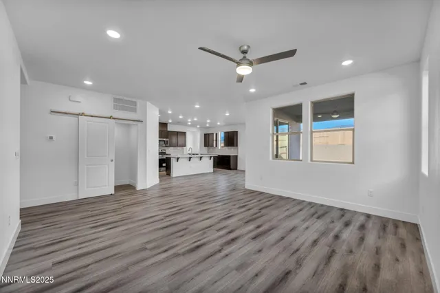 a view of an empty room with a window and wooden floor