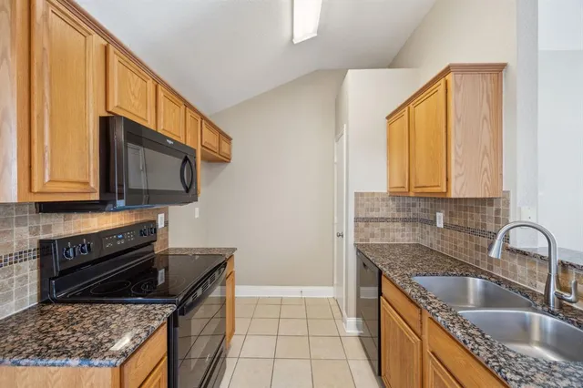 a kitchen with granite countertop a sink a stove and cabinets