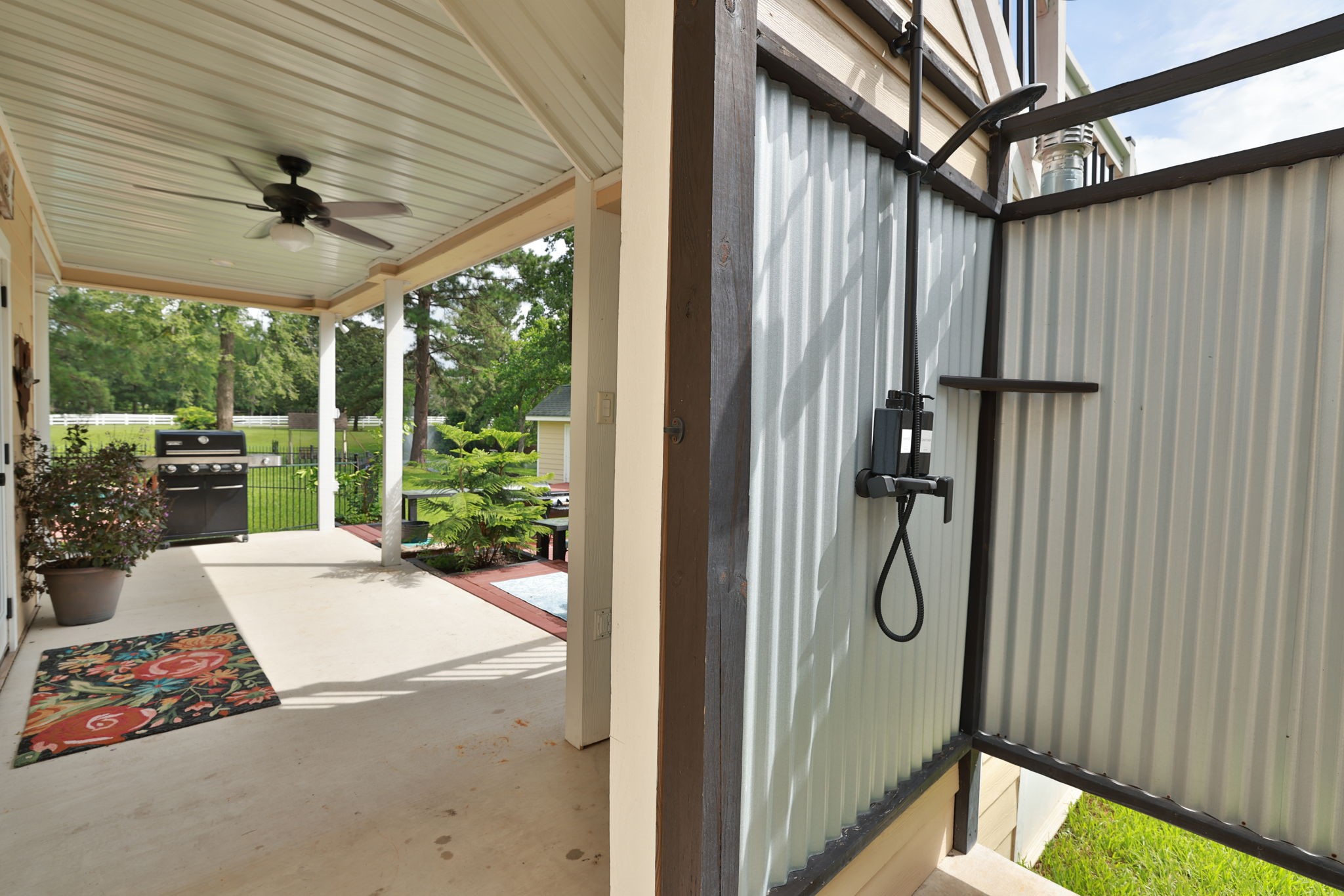 34310 High Point Drive Magnolia, TX 77355 - Photo 40 of 48 This photo shows a covered patio area with a ceiling fan and a convenient outdoor shower. Wonderful outdoor living space at it's finest!