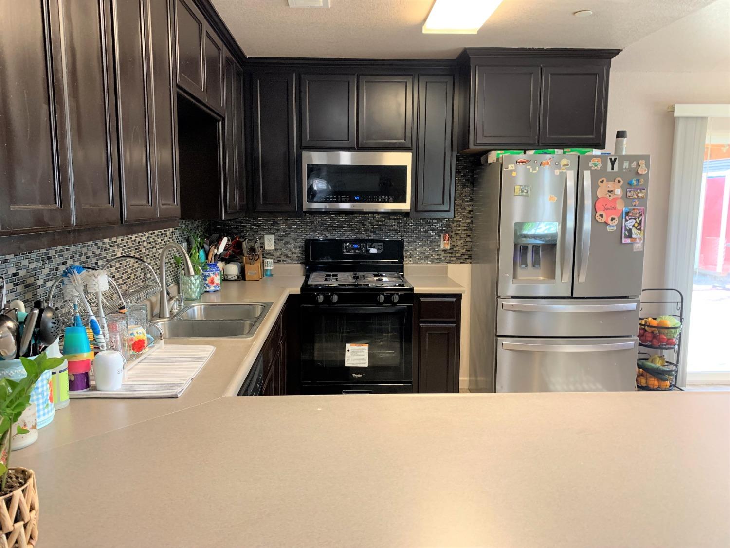 348 Silva Street Mendota, CA 93640 - Photo 6 of 24 a kitchen with granite countertop stainless steel appliances and wooden cabinets