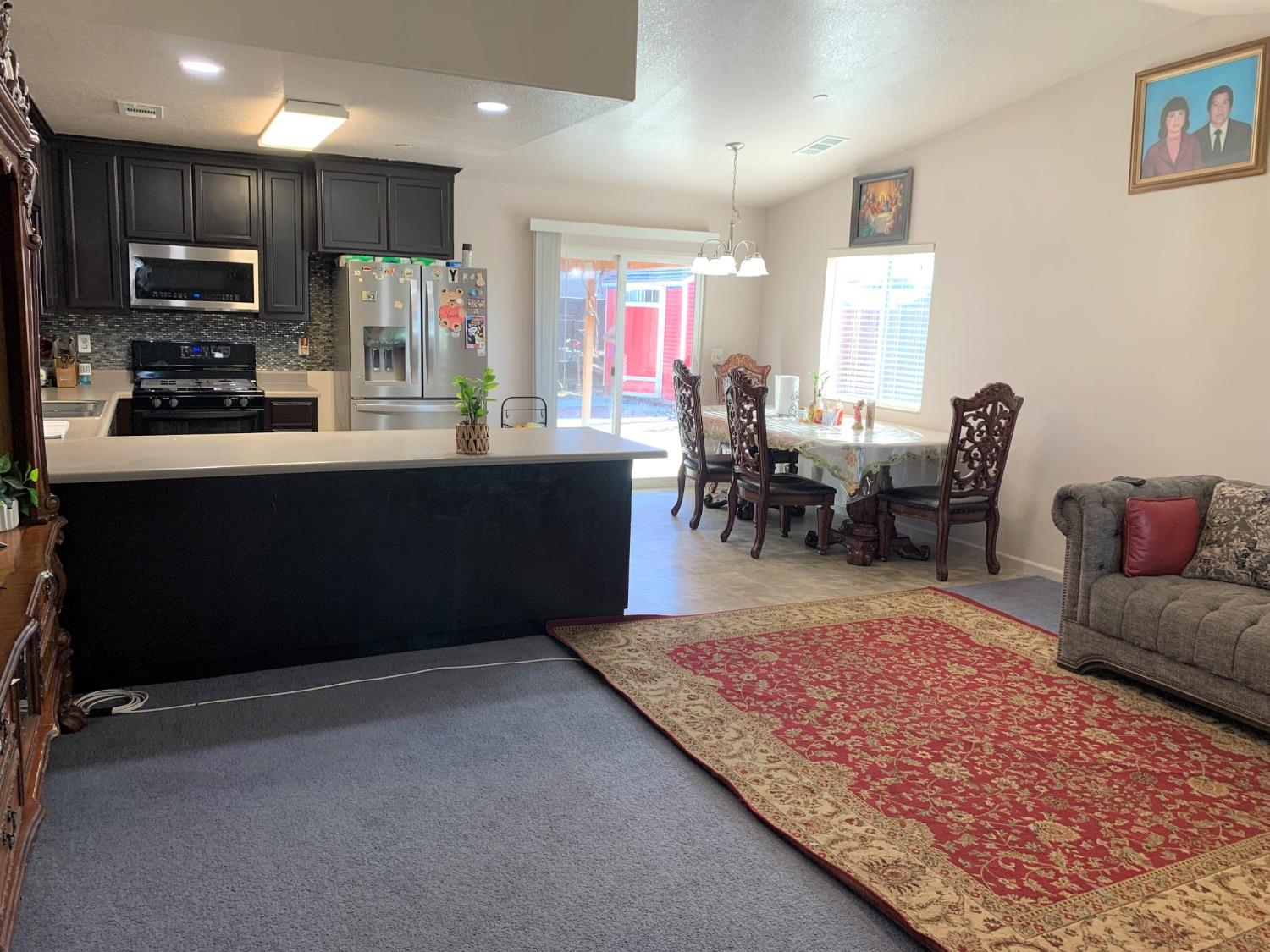 348 Silva Street Mendota, CA 93640 - Photo 10 of 24 a living room with stainless steel appliances kitchen island granite countertop furniture a rug and a view of kitchen