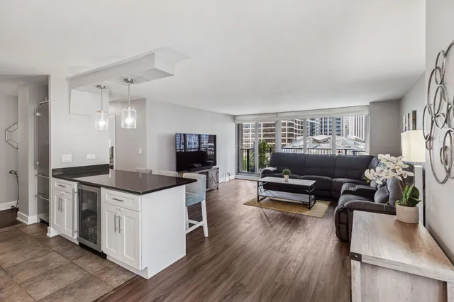 a kitchen with stainless steel appliances kitchen island granite countertop a stove a refrigerator a dining table and chairs with wooden floor