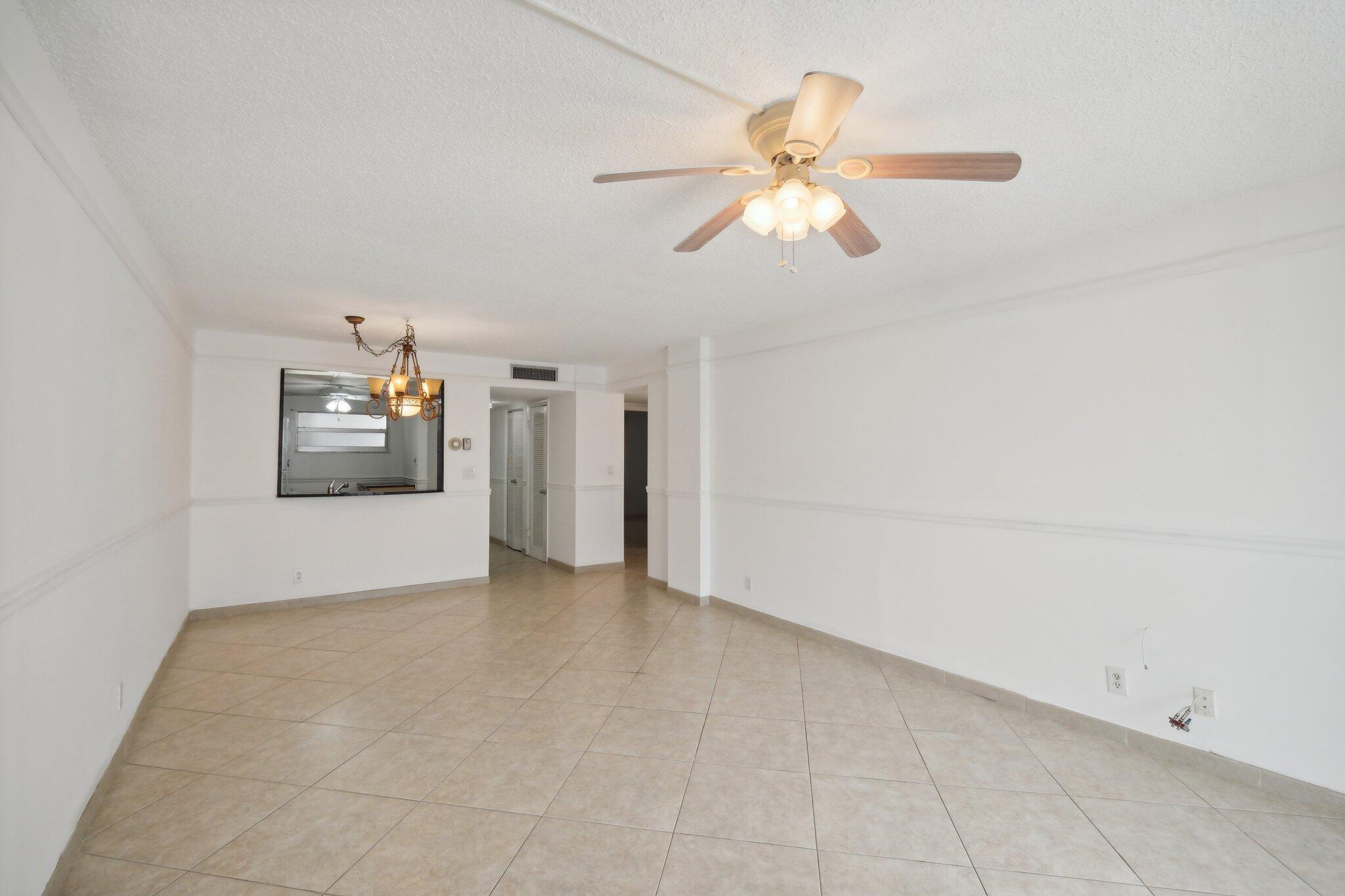 3580 South Ocean Boulevard, Unit 4C South Palm Beach, FL 33480 - Photo 11 of 36 an empty room with chandelier fan and windows