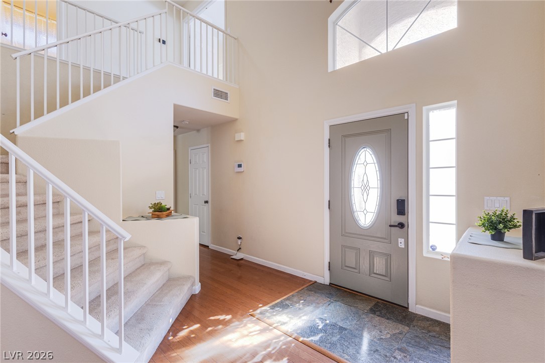 253 Camelback Ridge Avenue Henderson, NV 89012 - Photo 16 of 26 Double-height ceilings and tall windows illuminate a welcoming entryway with tiled and wood flooring.