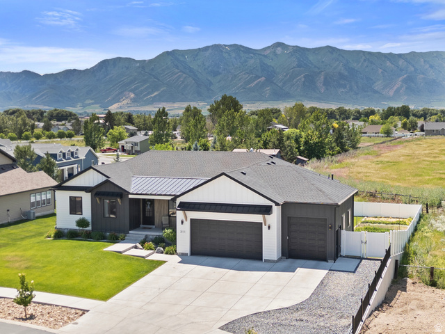 3111 South 1250 West Logan, UT 84321 - Photo 46 of 51 Modern farmhouse exterior with a combination of white siding and dark grey accents, featuring a two-car garage and an additional single-car garage