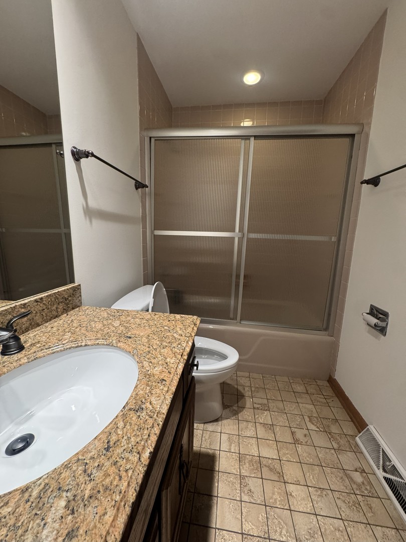 5145 Washington Street, Unit 2 Downers Grove, IL 60515 - Photo 13 of 16 a bathroom with a granite countertop sink a toilet a mirror and shower