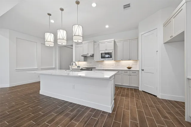 a kitchen with stainless steel appliances granite countertop a sink dishwasher a stove and white cabinets with wooden floor