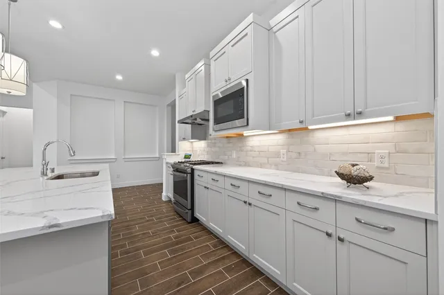 a kitchen with granite countertop a sink stainless steel appliances and cabinets