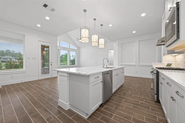 a large kitchen with granite countertop a large counter top a sink a window and stainless steel appliances