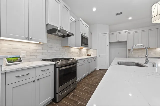 a kitchen with stainless steel appliances granite countertop a sink a stove and a refrigerator