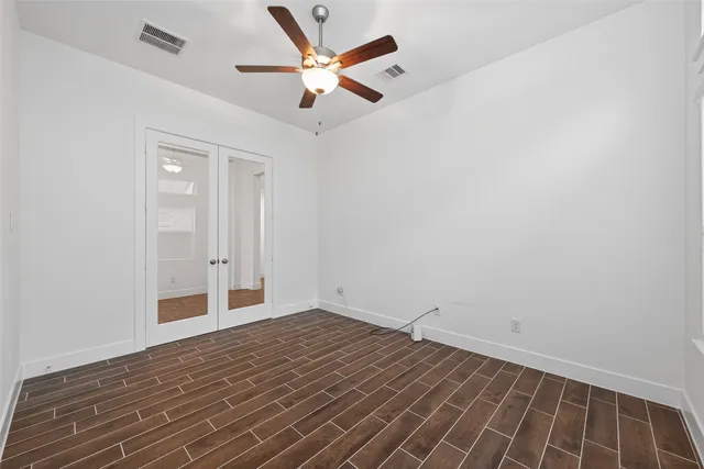an empty room with wooden floor fan and windows