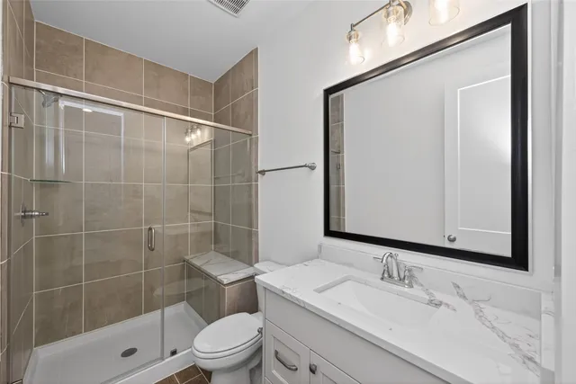 a bathroom with a granite countertop sink a toilet and shower