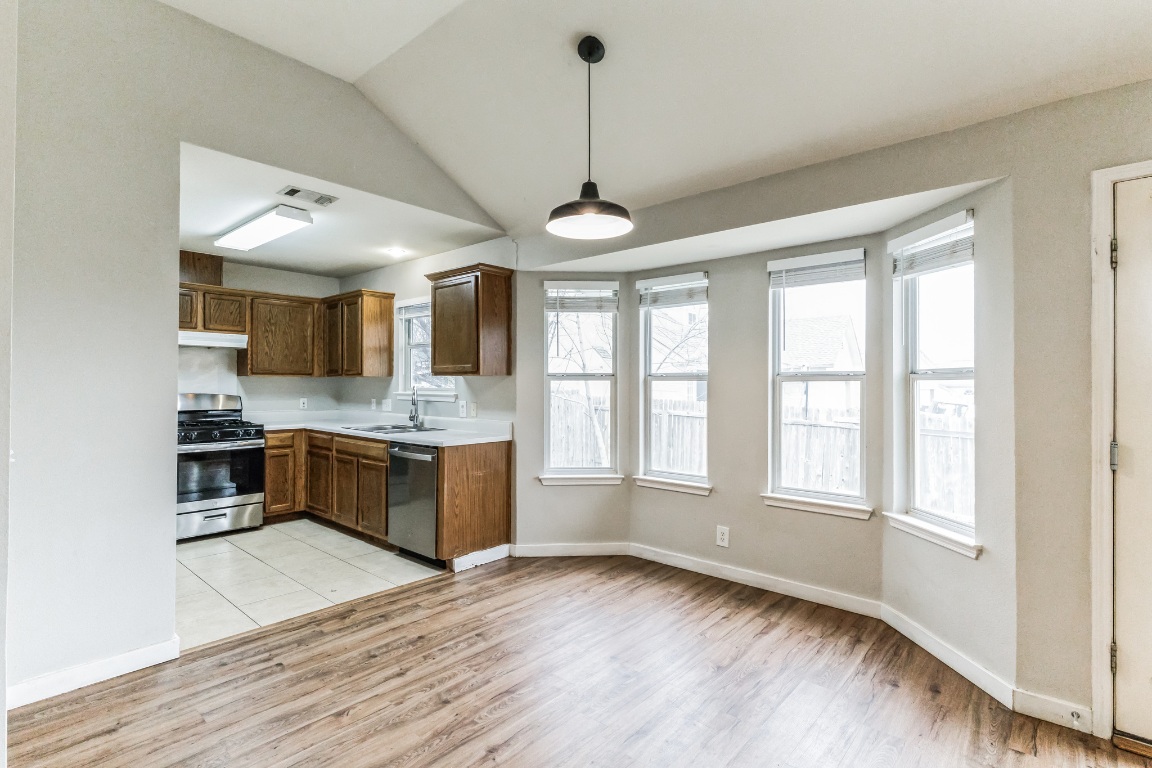 313 Caladium Drive Georgetown, TX 78626 - Photo 10 of 36 a large kitchen with stainless steel appliances granite countertop a stove a sink dishwasher and white cabinets with wooden floor