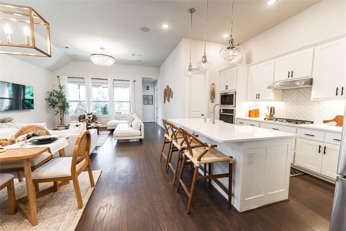 608 Pecan Bottom Trail Georgetown, TX 78628 - Photo 30 of 30 Kitchen with decorative backsplash, open floor plan, white cabinetry, a center island with sink, and a breakfast bar area