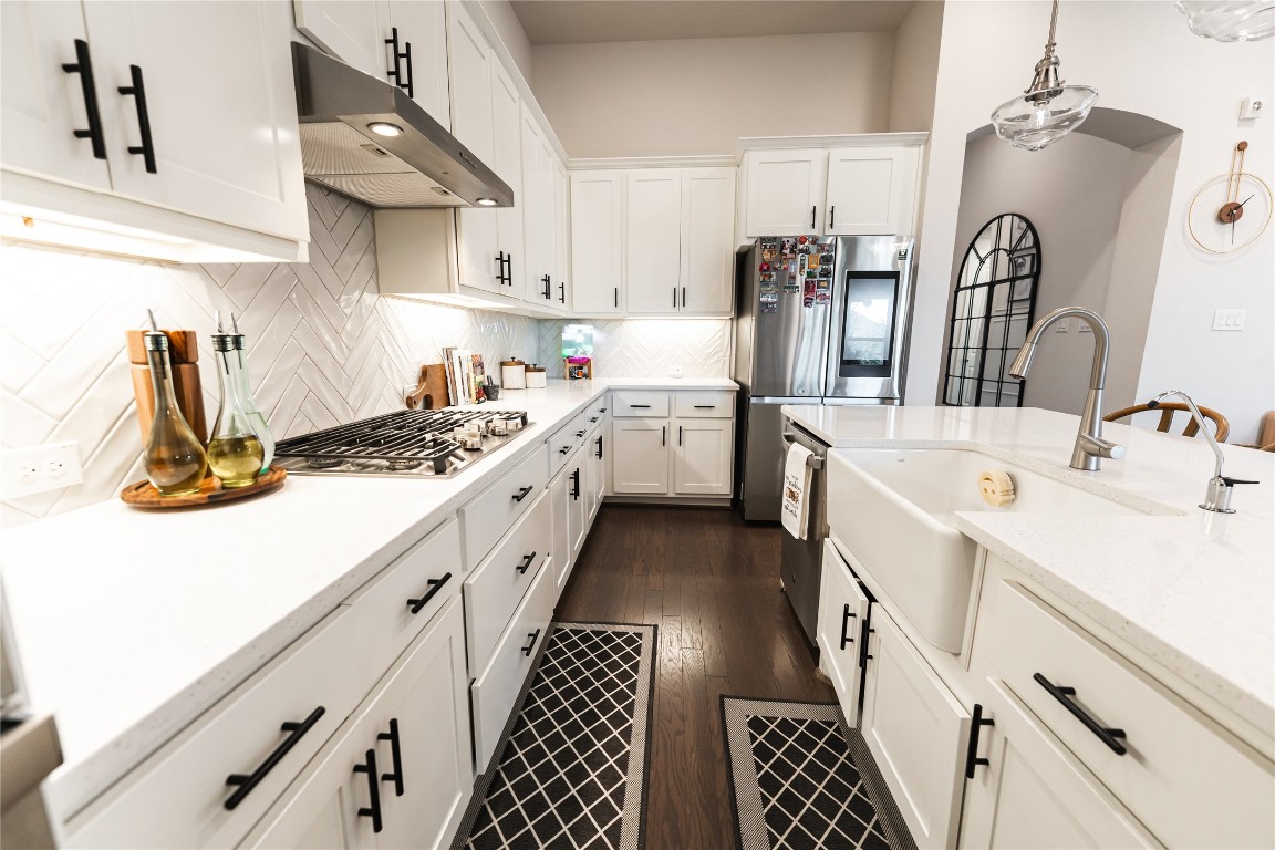 608 Pecan Bottom Trail Georgetown, TX 78628 - Photo 6 of 30 Kitchen featuring light stone counters, decorative light fixtures, white cabinets, and dark wood-type flooring