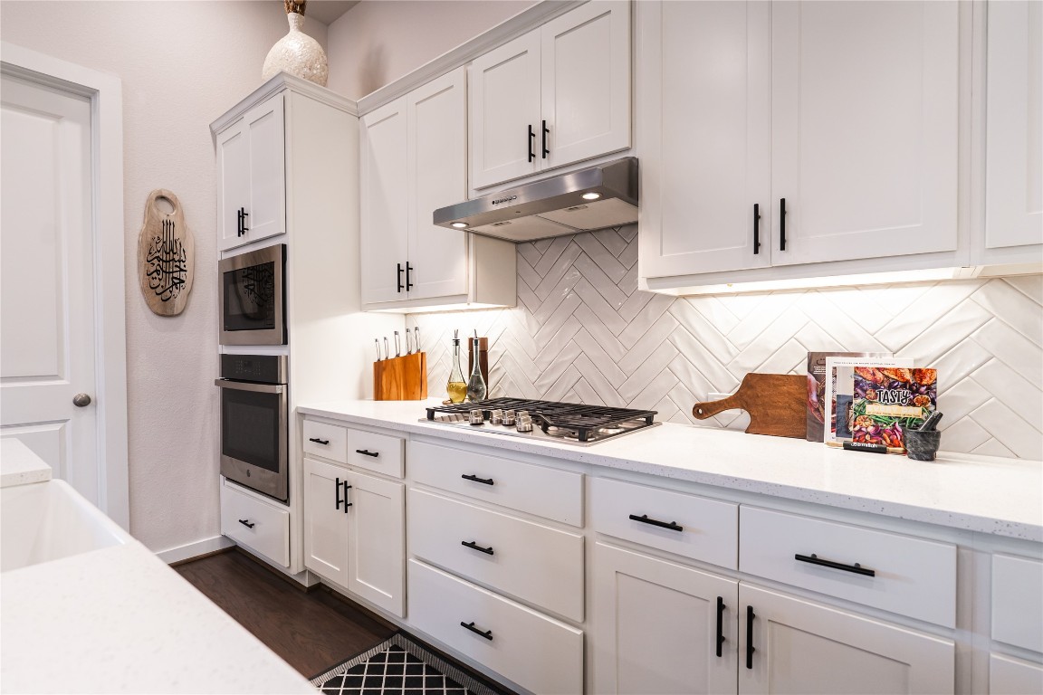 608 Pecan Bottom Trail Georgetown, TX 78628 - Photo 7 of 30 Kitchen with white cabinetry, appliances with stainless steel finishes, light stone counters, and under cabinet range hood